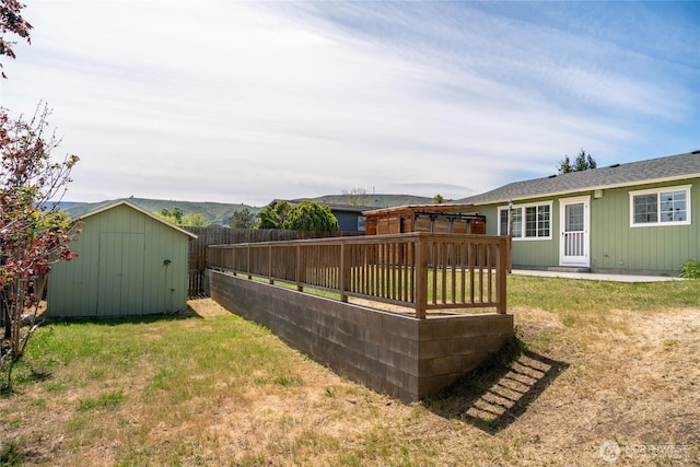 view of yard with a deck, an outbuilding, a shed, and a fenced backyard