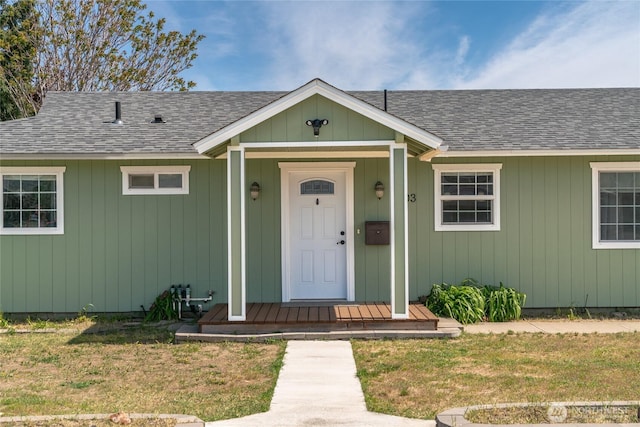 view of front of home with a shingled roof and a front yard