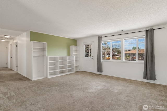 carpeted spare room with a textured ceiling, visible vents, and baseboards