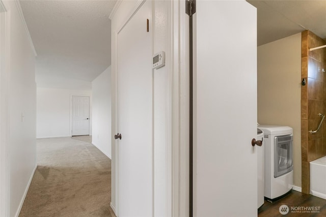 hallway featuring carpet floors, baseboards, and washing machine and dryer