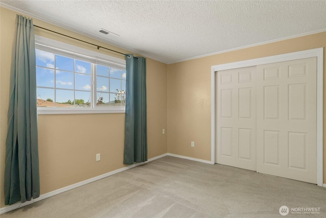 unfurnished bedroom featuring a textured ceiling, carpet, baseboards, visible vents, and a closet