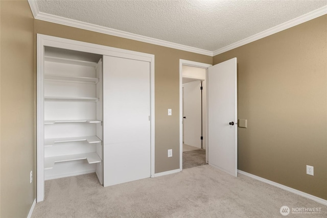unfurnished bedroom with a textured ceiling, carpet, baseboards, ornamental molding, and a closet