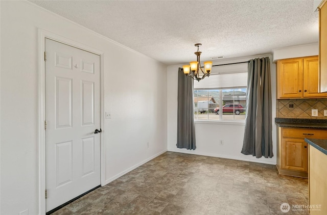 unfurnished dining area with an inviting chandelier, a textured ceiling, baseboards, and visible vents