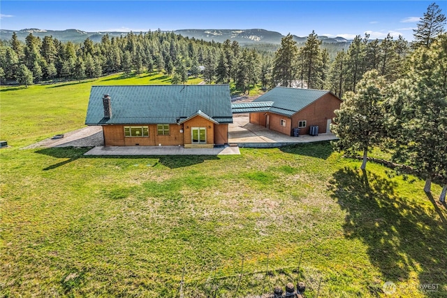 view of subject property with a mountainous background and a forest
