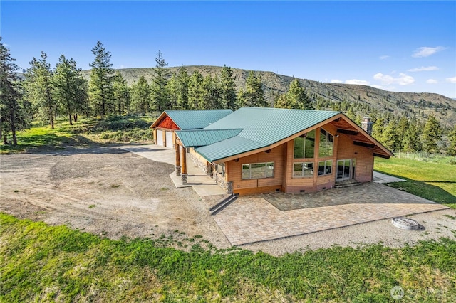 rear view of house with a standing seam roof, a mountain view, metal roof, and a garage