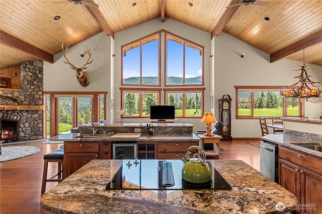kitchen featuring an island with sink, high vaulted ceiling, black electric stovetop, dishwasher, and a sink