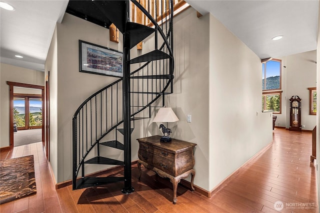stairs featuring wood finished floors, baseboards, and recessed lighting