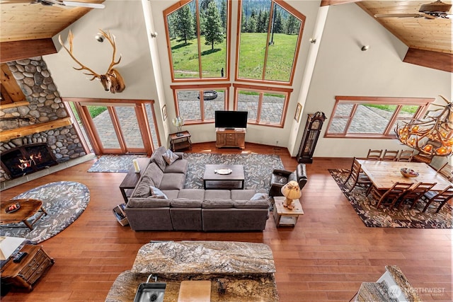 living room featuring a fireplace, hardwood / wood-style floors, wood ceiling, and high vaulted ceiling