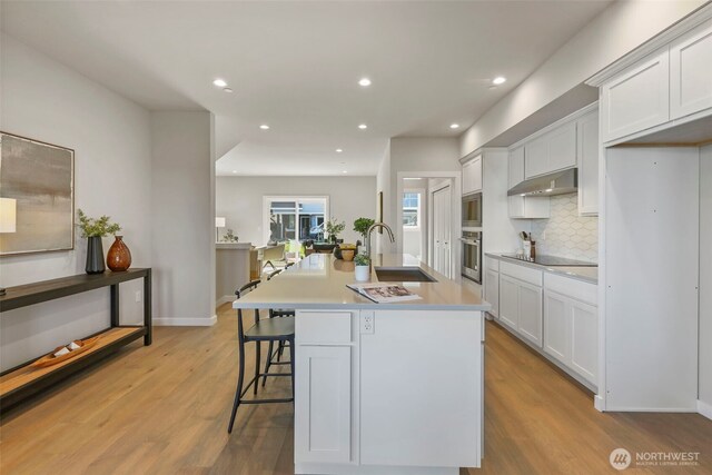 26632 NE 143rd Pl, Duvall, WA 98019 - kitchen featuring a sink, appliances with stainless steel finishes, light wood-style flooring, an island with sink, and under cabinet range hood