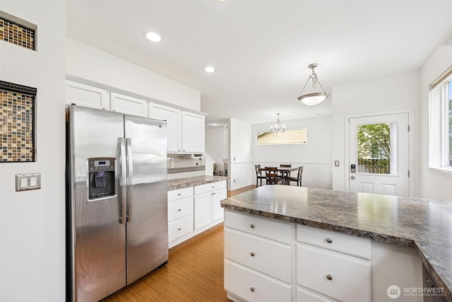 kitchen featuring an inviting chandelier, stainless steel fridge with ice dispenser, light wood finished floors, and white cabinetry