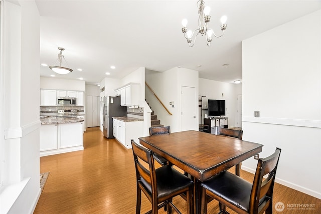 dining area featuring stairs, baseboards, recessed lighting, light wood finished floors, and a notable chandelier