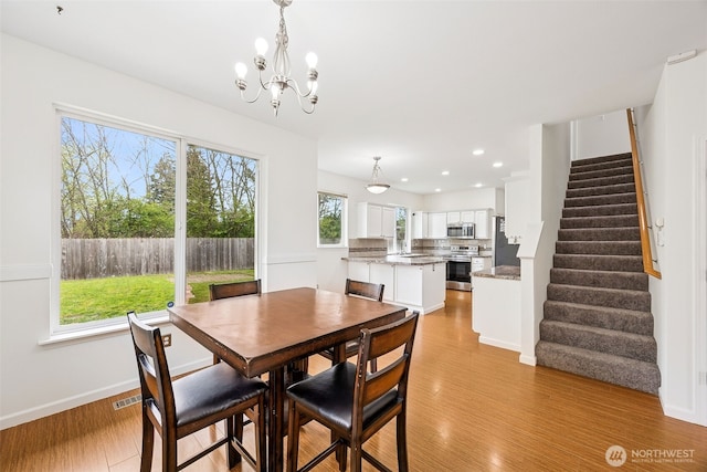 dining area with light wood-type flooring, stairway, baseboards, a notable chandelier, and recessed lighting