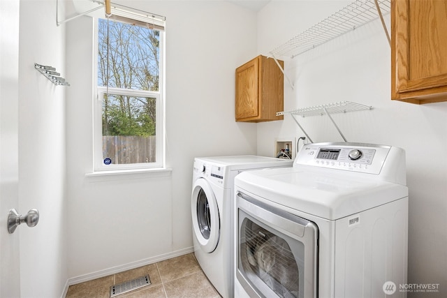 clothes washing area with washer and dryer, light tile patterned flooring, cabinet space, baseboards, and visible vents