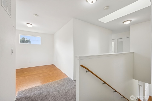 interior space with baseboards, visible vents, wood finished floors, and carpet