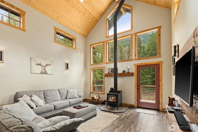 living area with wood-type flooring, a wood stove, a healthy amount of sunlight, high vaulted ceiling, and wooden ceiling