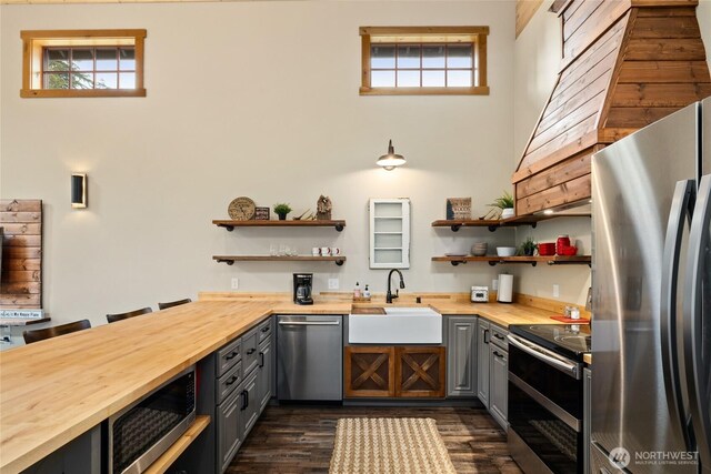 kitchen featuring appliances with stainless steel finishes, gray cabinets, open shelves, and wood counters