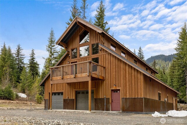 view of front of property featuring a garage, board and batten siding, driveway, and a wooded view