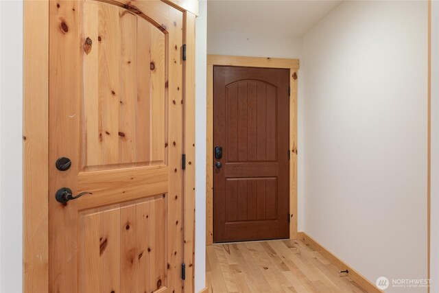 doorway to outside with baseboards and light wood-style flooring