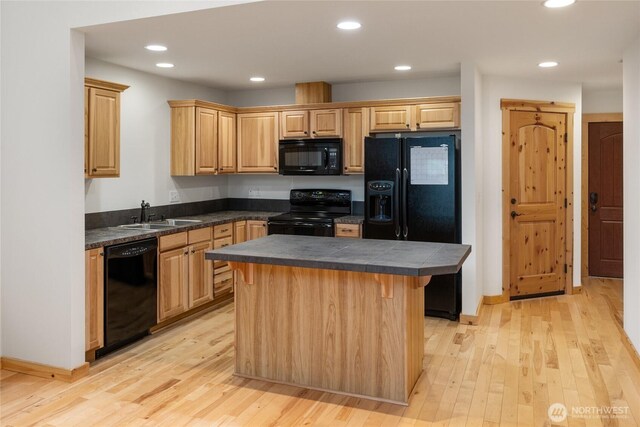 kitchen featuring light wood-type flooring, a sink, black appliances, and a center island