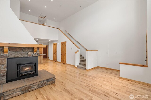 unfurnished living room featuring a fireplace, recessed lighting, stairway, and light wood-type flooring