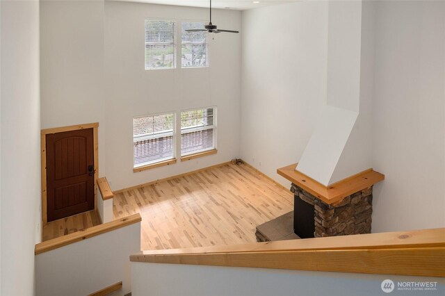 interior space featuring a ceiling fan, a high ceiling, and wood finished floors