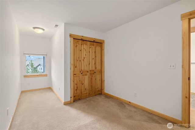 unfurnished bedroom with a closet, baseboards, carpet flooring, and visible vents