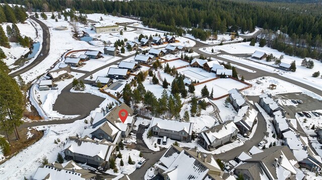 snowy aerial view featuring a residential view and a wooded view