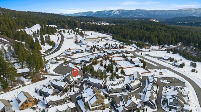 snowy aerial view with a residential view, a mountain view, and a wooded view