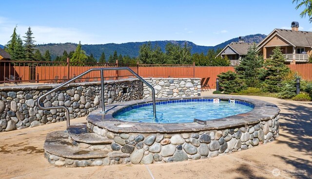view of pool featuring a fenced backyard, a mountain view, and an in ground hot tub