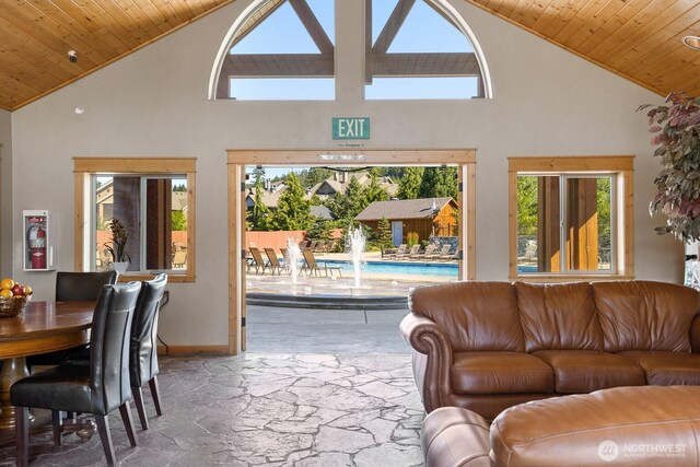 living room with high vaulted ceiling, stone floors, baseboards, and wood ceiling
