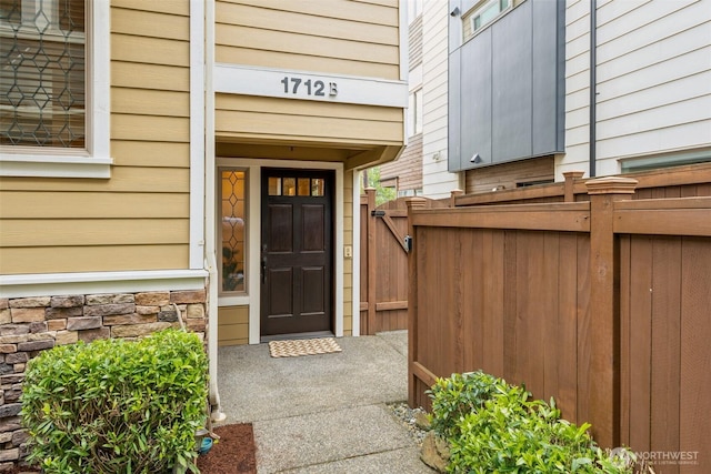 entrance to property featuring fence and stone siding
