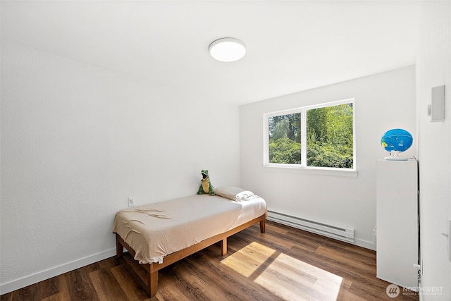 bedroom with baseboards, baseboard heating, and wood finished floors