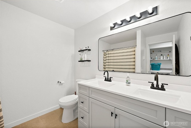full bath with double vanity, toilet, tile patterned floors, and a sink
