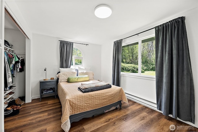 bedroom featuring a closet, a baseboard heating unit, and wood finished floors