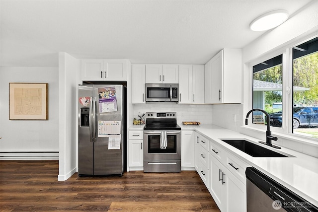 kitchen featuring a baseboard radiator, light countertops, white cabinets, a sink, and stainless steel appliances