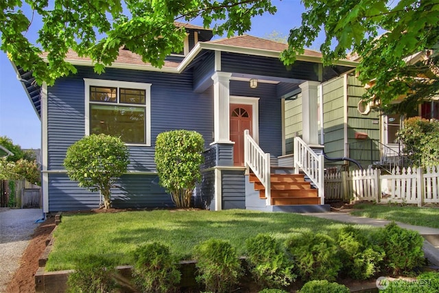 bungalow-style home featuring a shingled roof, fence, and a front yard
