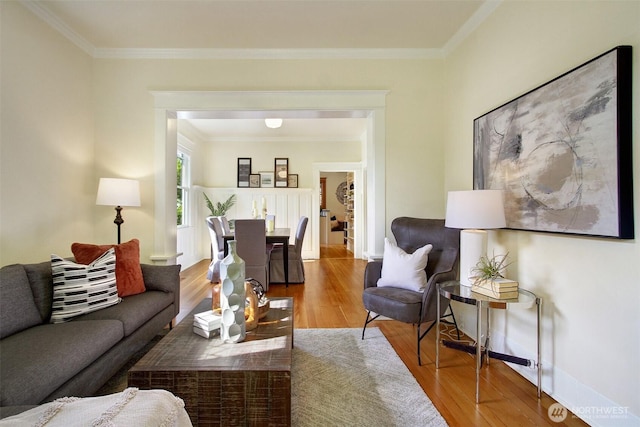 living area featuring crown molding, baseboards, and wood finished floors