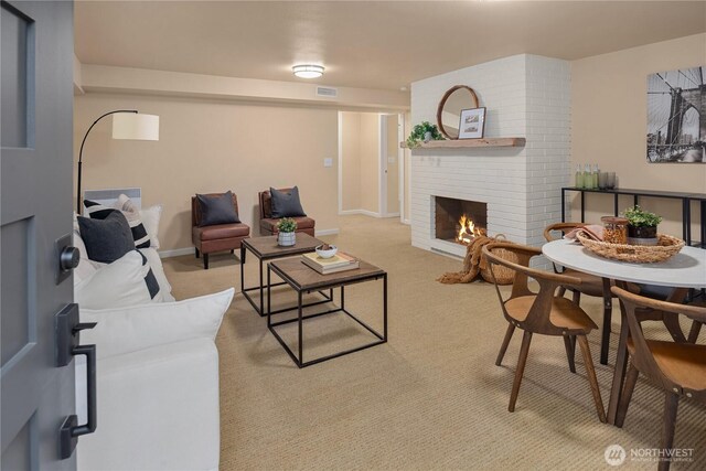 living room featuring a brick fireplace, baseboards, visible vents, and light carpet