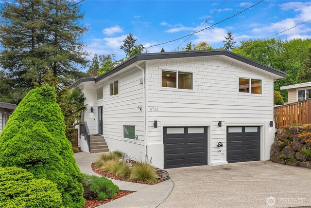 view of side of home featuring concrete driveway and an attached garage
