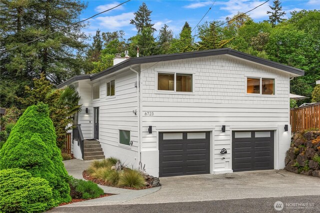 view of home's exterior featuring an attached garage, a chimney, and concrete driveway