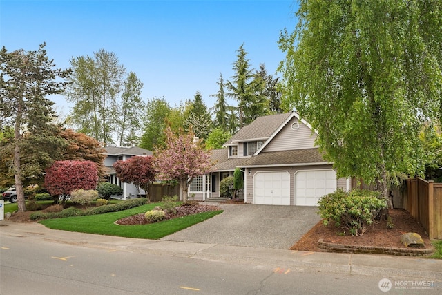 view of front of property with fence, an attached garage, and driveway