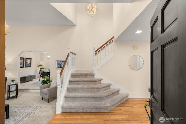 entryway with recessed lighting, arched walkways, light wood finished floors, and stairway