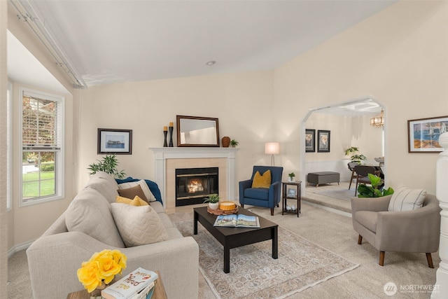 living area with an inviting chandelier, light carpet, vaulted ceiling, and a tile fireplace