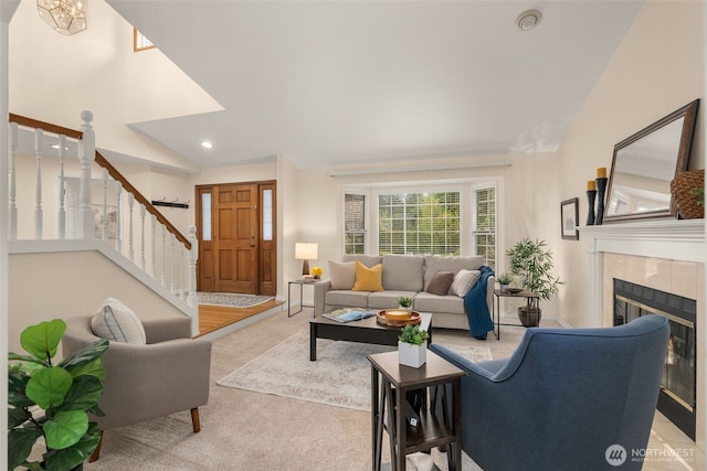 living room featuring stairs, lofted ceiling, light colored carpet, recessed lighting, and a tile fireplace
