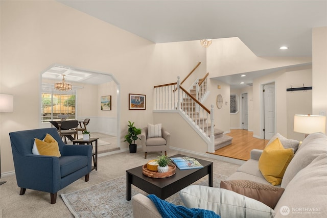 living room with baseboards, stairway, light colored carpet, a chandelier, and arched walkways