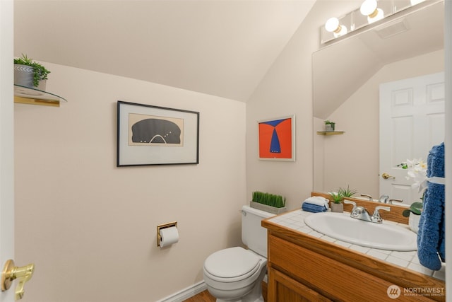 bathroom with toilet, vaulted ceiling, and vanity