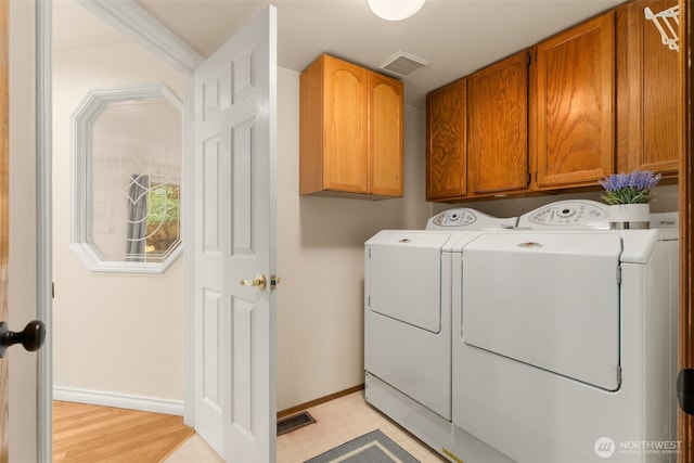 washroom featuring cabinet space, baseboards, visible vents, and washing machine and dryer