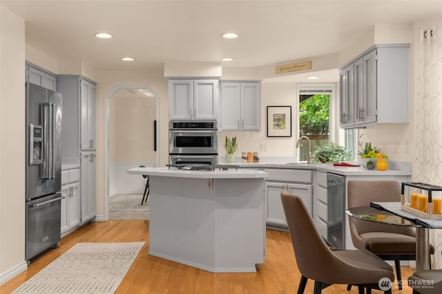 kitchen with light wood-style floors, light countertops, a sink, and appliances with stainless steel finishes