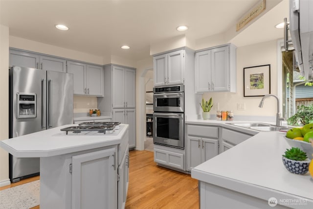 kitchen featuring a sink, light wood-style floors, light countertops, gray cabinets, and stainless steel appliances