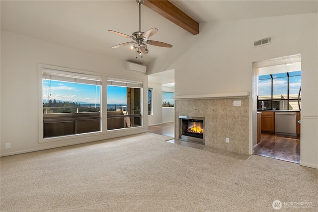 1113 5th Ave S Unit 301, Edmonds, WA 98020 - unfurnished living room with carpet, a wall mounted AC, ceiling fan, a tile fireplace, and beam ceiling